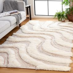 a living room with a white couch and large rug on the floor in front of a window