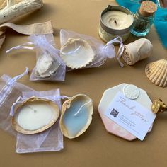 seashells and candles are sitting on a table next to some other sea shells