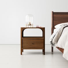 a bed with a night stand next to it on top of a white carpeted floor