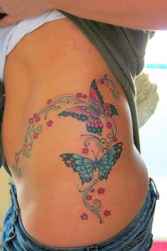 a woman with a butterfly tattoo on her stomach is holding onto the side of her belly