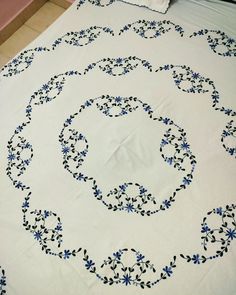 an embroidered bed spread with blue flowers on it