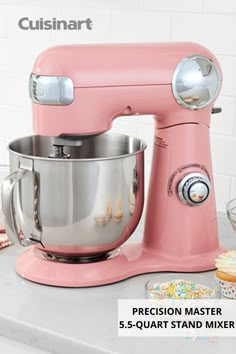 a pink mixer sitting on top of a counter next to cupcakes and cookies