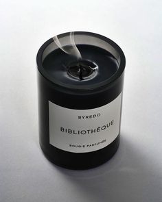 a black candle with a white label on the top and bottom that reads bibliotique