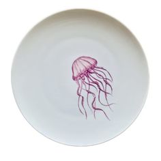 a white plate with a purple jellyfish on it's side and the bottom