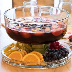 a glass bowl filled with fruit on top of a wooden table