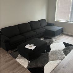 a living room with a black couch and white rug