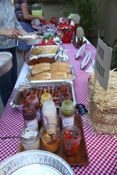 a buffet table with hotdogs, condiments and other foods on it