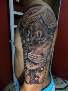 a man with a tattoo on his arm has a lion and clock on it's shoulder