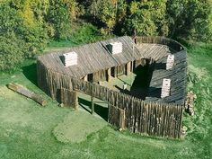 an aerial view of a wooden structure in the middle of a field with trees around it