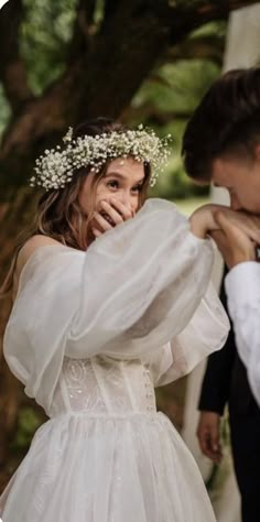 a woman in a wedding dress is touching the forehead of a man