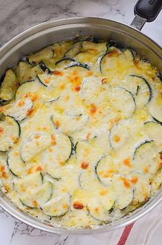 a pan filled with cheese and zucchini on top of a table