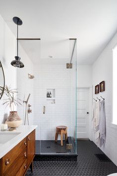 a bathroom with a walk in shower next to a white sink and wooden cabinetry