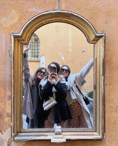 three women taking a selfie in front of a mirror with their hands up to the camera