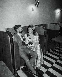 a man and woman sitting next to each other in a room with black and white checkered flooring