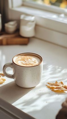 a cappuccino sitting on top of a white counter next to a window