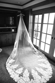 a wedding veil is hanging from the ceiling in front of an open window with flowers on it