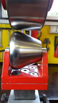 a machine that is sitting on top of a red stand with tools in the background