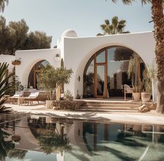 an outdoor swimming pool surrounded by palm trees and potted plants next to a white building