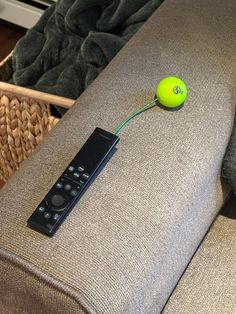 a remote control sitting on top of a couch next to a green ball and wicker basket