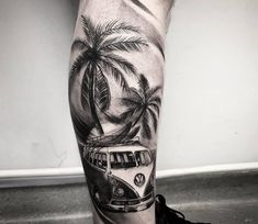 a man's leg with a bus and palm trees on the beach in black and white