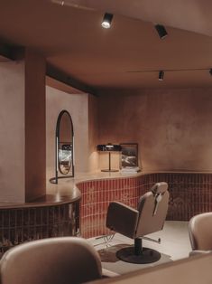 a room with chairs and a mirror in the corner next to a wall that has red tiles on it