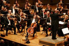 conductor and orchestra performing on stage with audience