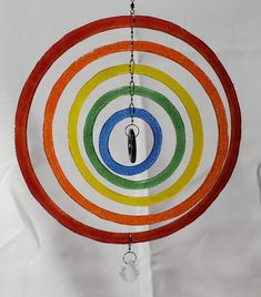 a multicolored circular wind chime hanging from a chain on a white background