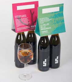 three bottles of wine and a glass on a white table with a card in the middle