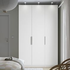 a bedroom with a bed and white cupboards next to a door on the wall