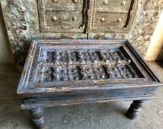 an old wooden table with ornate carvings on the top and bottom, sitting in front of two drawers