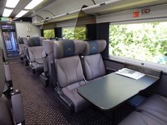 the inside of an empty train car with tables and chairs on each side, looking out the window