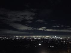 the city lights are lit up in the dark night sky as seen from an overlook