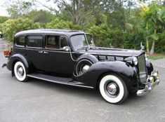 an old black car is parked on the street