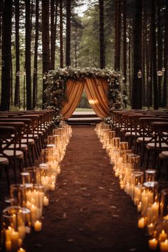 an outdoor wedding setup with candles and draping on the aisle, surrounded by tall trees