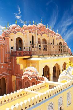 an ornate building with many arches and pillars on the roof, surrounded by blue skies