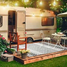 an rv is parked in the backyard with patio furniture and lights strung over it's windows