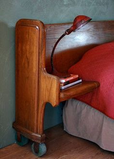 a bed with a wooden headboard and red sheets on it, next to a nightstand