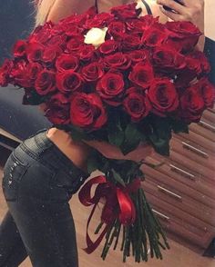 a woman taking a selfie with her cell phone while holding a large bouquet of roses