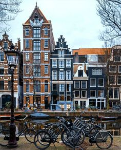 several bicycles are parked in front of some buildings on the other side of a canal