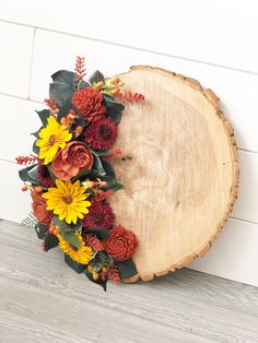 an arrangement of flowers is placed on top of a wood slice that has been cut in half