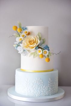 a white and blue cake with yellow flowers on top