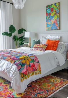 a bed with colorful pillows and blankets on top of it next to a chandelier