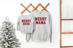 two sweatshirts hanging on a clothes rack next to a christmas tree and towel rack