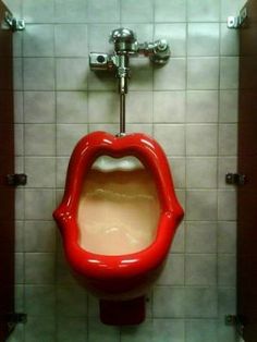 a urinal that has been painted red and is in a bathroom with tiled walls