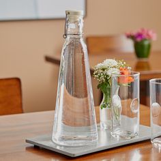 there are two vases on the table and one is empty with flowers in it