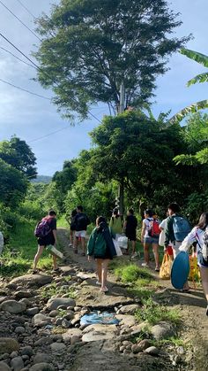 many people are walking down a path with bags and frisbees in hand