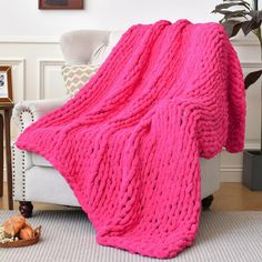 a pink blanket sitting on top of a white chair