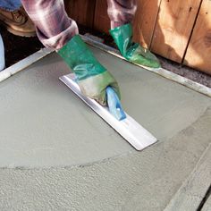 a person in green rubber gloves painting concrete