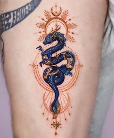 a woman's thigh with a blue dragon tattoo on her leg and an orange star in the middle