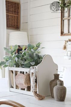 a planter filled with green plants sitting on top of a white table next to a lamp